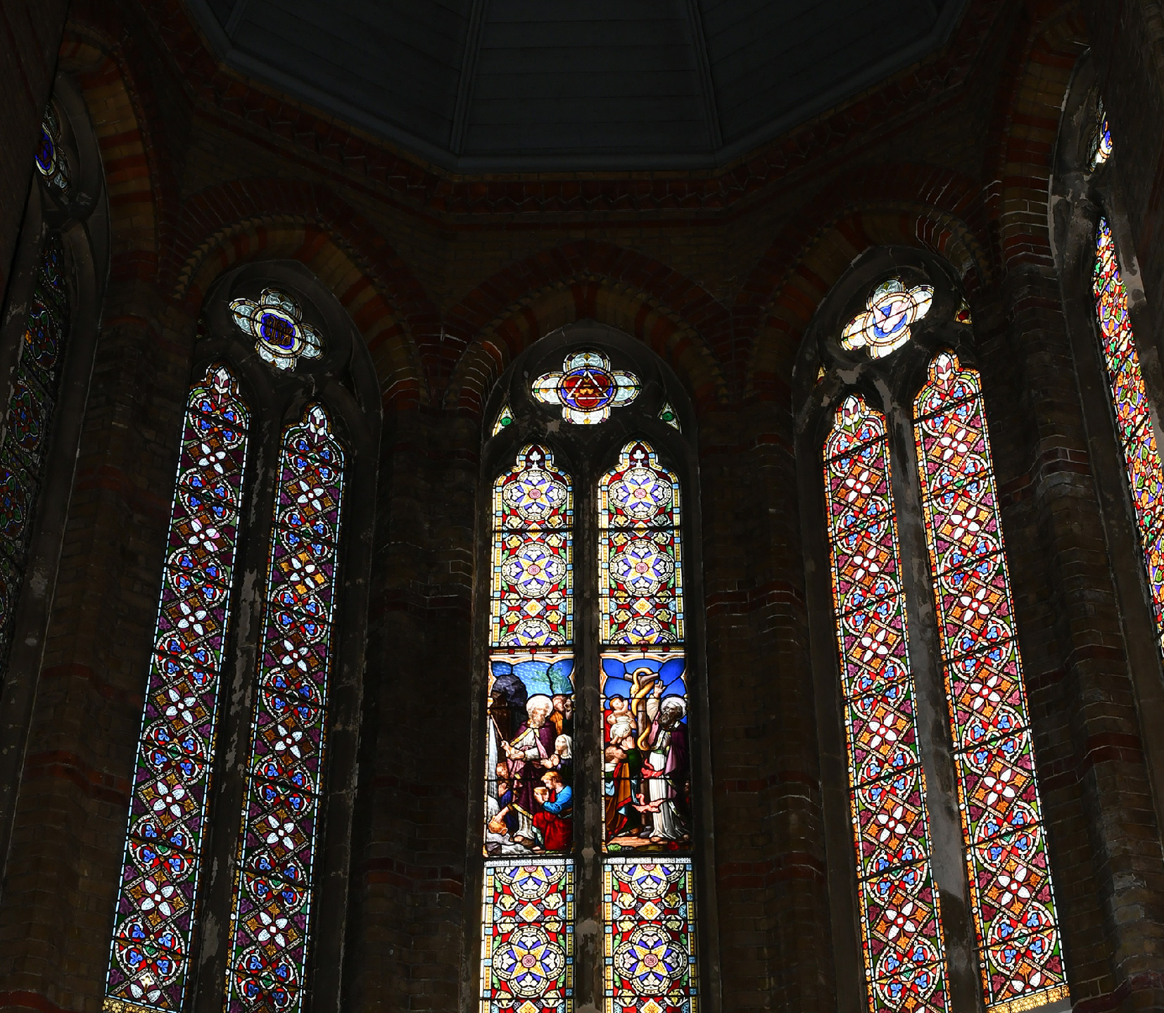 3 of the apse’s stained glass windows backlit and showing their full colour.